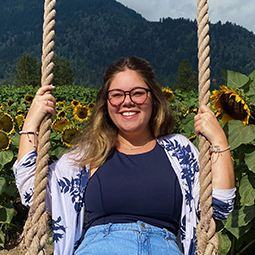 International student Gabriella enjoys a field of sunflowers in BC, with mountains visible in the background.