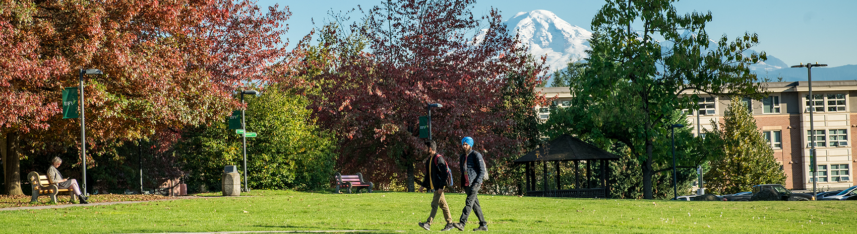 Two students walk across a field; Mount Baker can be seen in the background.